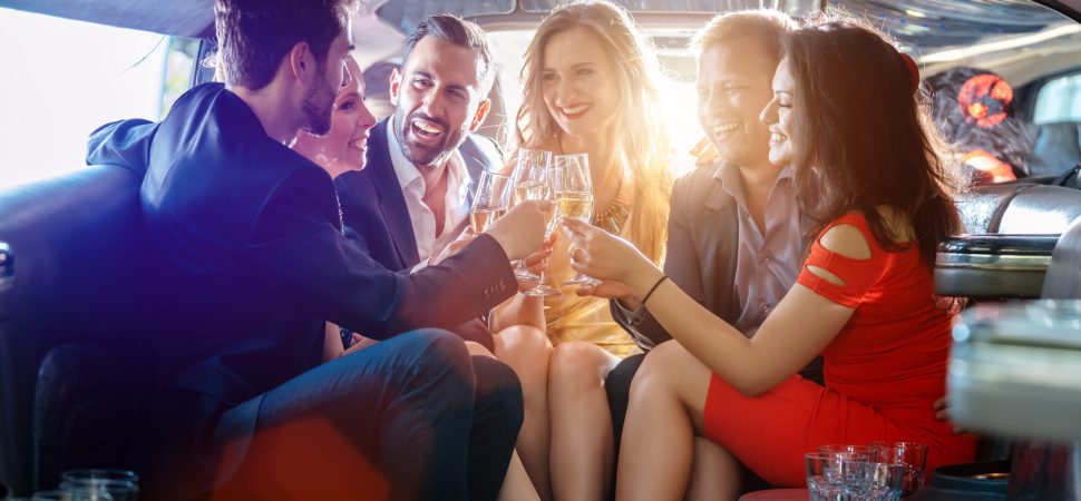 Group of friends having a night out in a limo with glasses of champagne
