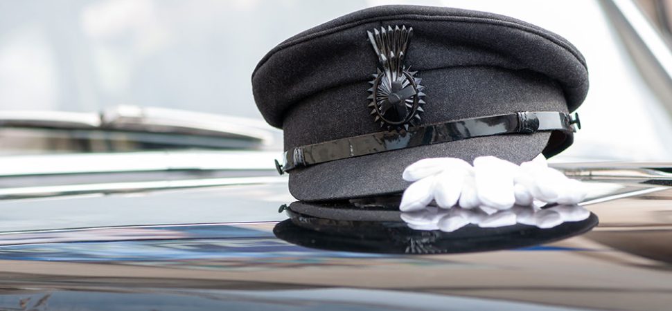 Chauffeur's hat sitting on the hood of a limo